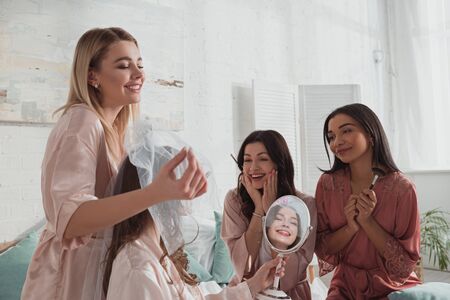 Multiethnic women admiring beautiful bride at bachelorette party in roomの写真素材