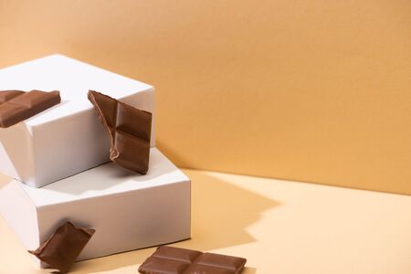 delicious milk chocolate pieces and square cubes on beige backgroundの写真素材
