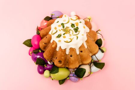 High angle view of colorful wreath with tasty easter cake on pink background
