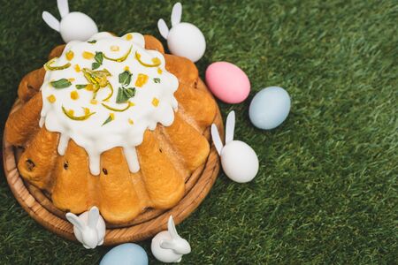 High angle view of easter cake with colorful chicken eggs and decorative bunnies on green background