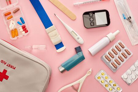 Top view of first aid kit, pills and medical objects on pink backgroundの写真素材