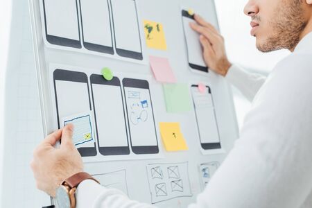 Cropped view of designer creative design of mobile website with templates on whiteboard in officeの写真素材