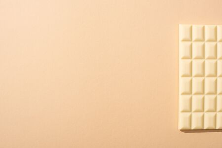 top view of delicious white chocolate bar on beige background