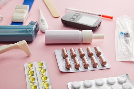 Selective focus of capsules, pills and medical objects on pink background