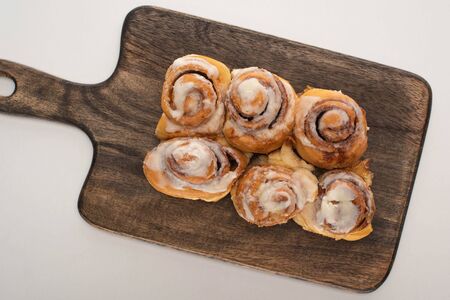 top view of fresh homemade cinnamon rolls on wooden cutting board on white backgroundの写真素材