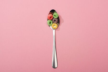 top view of bright colorful breakfast cereal in spoon on pink backgroundの写真素材