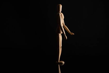Wooden doll in standing position on black backgroundの写真素材