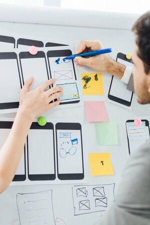 Selective focus of designers planning user experience design of mobile website on whiteboard