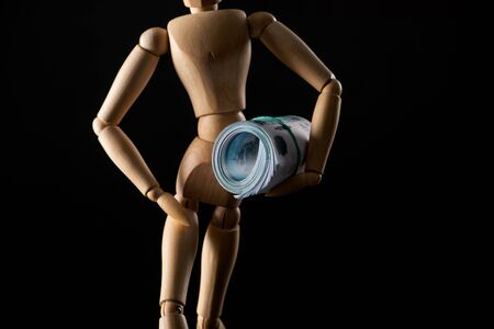 Wooden doll with money isolated on blackの写真素材