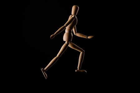 Wooden doll imitating running isolated on blackの写真素材