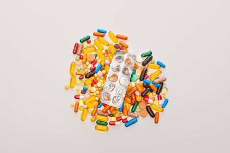 Top view of empty blister pack on heart from colorful pills isolated on whiteの写真素材