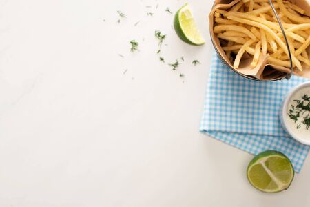 top view of fried french fries, garlic sauce and sliced lime on whiteの写真素材