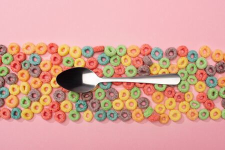 top view of bright colorful breakfast cereal and spoon on pink backgroundの写真素材