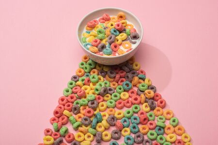 bright colorful breakfast cereal with milk in bowl and on pink backgroundの写真素材