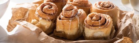 close up view of fresh homemade cinnamon rolls on parchment paper, panoramic shot