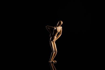 Wooden doll imitating backache on blackの写真素材