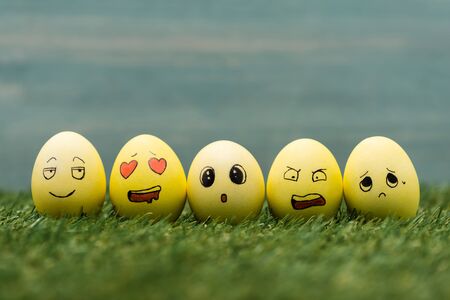 Easter eggs with different facial expressions on grass