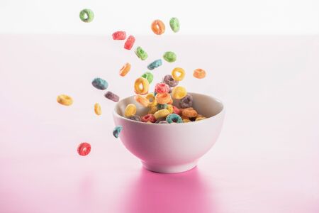 bright multicolored breakfast cereal in bowl on pink backgroundの写真素材