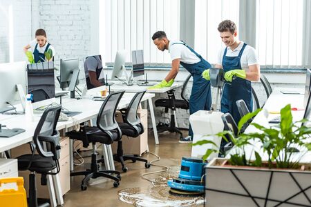 multicultural team of cleaners working in modern open space officeの写真素材