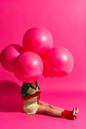 beautiful young woman holding balloons on pinkの写真素材