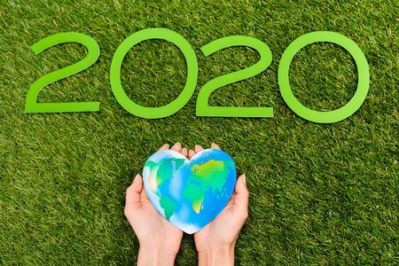 Cropped view of 2020 digits and globe in female hands on green, earth day conceptの写真素材