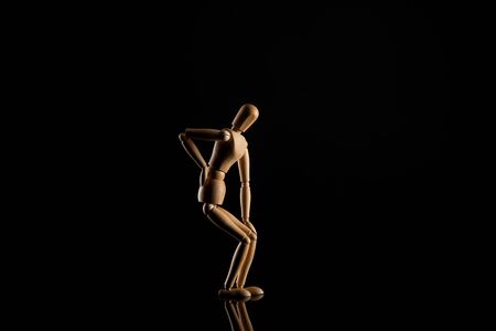 Wooden doll imitating backache on black backgroundの写真素材
