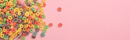 top view of bright colorful breakfast cereal scattered from bowl on pink background, panoramic shotの写真素材