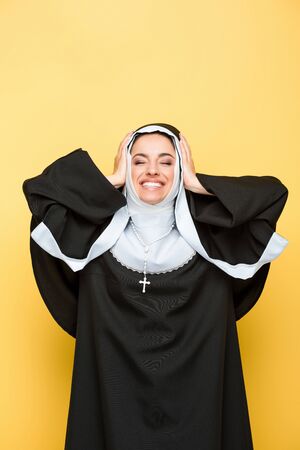 beautiful happy nun with closed eyes, on yellowの写真素材