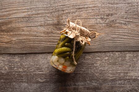top view of homemade tasty canned cucumbers in jar on wooden tableの写真素材