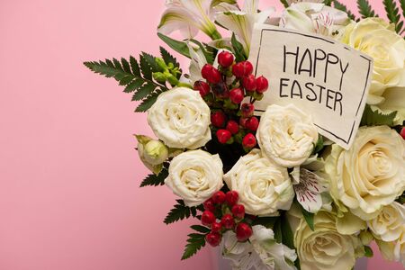 bouquet of flowers in festive gift box with happy Easter greeting card on pink backgroundの写真素材