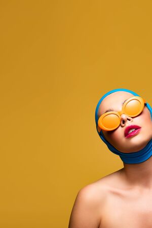 elegant naked girl in scarf and fashionable sunglasses, isolated on yellowの写真素材