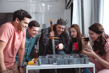 KYIV, UKRAINE - JANUARY 27, 2020: cheerfull man in costume of king playing labyrinth game with smiling friendsのeditorial素材