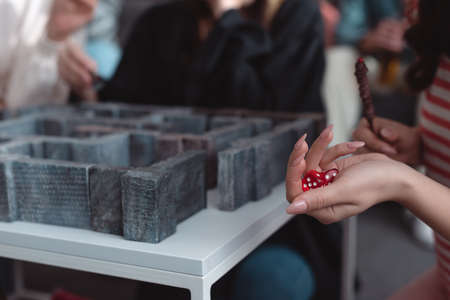 KYIV, UKRAINE - JANUARY 27, 2020: cropped view of girl holding dice near labyrinth board game on tableのeditorial素材