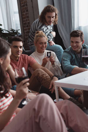 KYIV, UKRAINE - JANUARY 27, 2020: selective focus of cheerful girl holding card while playing mafia game with friendsのeditorial素材