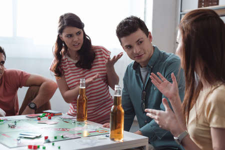 KYIV, UKRAINE - JANUARY 27, 2020: displeased girls gesturing near confused man while playing monopoly gameのeditorial素材