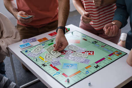 KYIV, UKRAINE - JANUARY 27, 2020: cropped view of man taking card while playing monopoly game with...