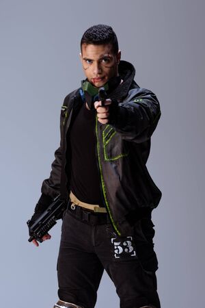handsome bi-racial cyberpunk player aiming gun isolated on grey