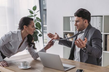 seductive secretary touching tie of shocked businessman while seducing him in officeの写真素材