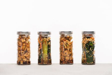 daikon radish and cucumber kimchi in jars isolated on whiteの写真素材
