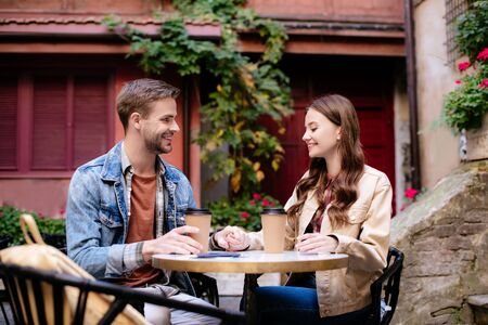 Selective focus of couple with disposable cups of coffee in cafe in cityの写真素材