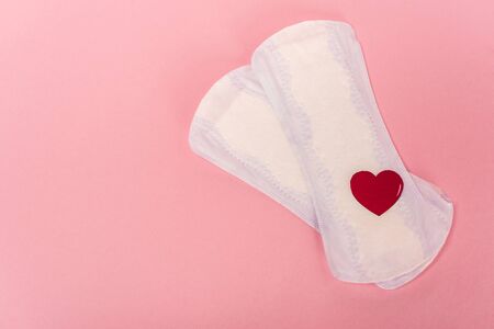 Top view of feminine pads with paper heart on pink backgroundの写真素材