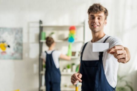 selective focus of happy and handsome cleaner holding blank cardの写真素材
