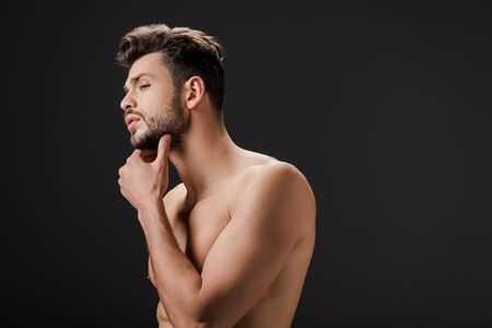 handsome sexy naked man touching beard isolated on blackの写真素材