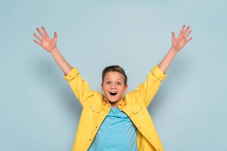 happy kid with outstretched hands looking at camera on blue backgroundの写真素材