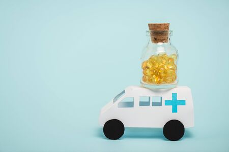 Jar of pills on toy ambulance car on blue backgroundの写真素材