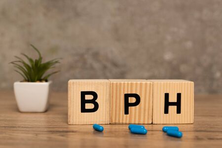 Selective focus of cubes with bph letters and pills with plant on wooden table on grey backgroundの写真素材