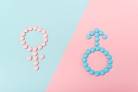 High angle view of male and female signs from hormonal pills on blue and pink surfaceの写真素材