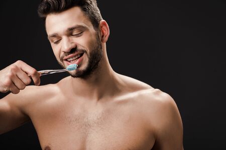 positive nude man with tooth brush isolated on blackの写真素材