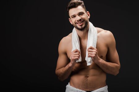 handsome brunette man with towel isolated on blackの写真素材