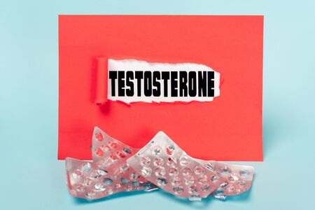 Paper with testosterone lettering and empty blisters of pills on blue background